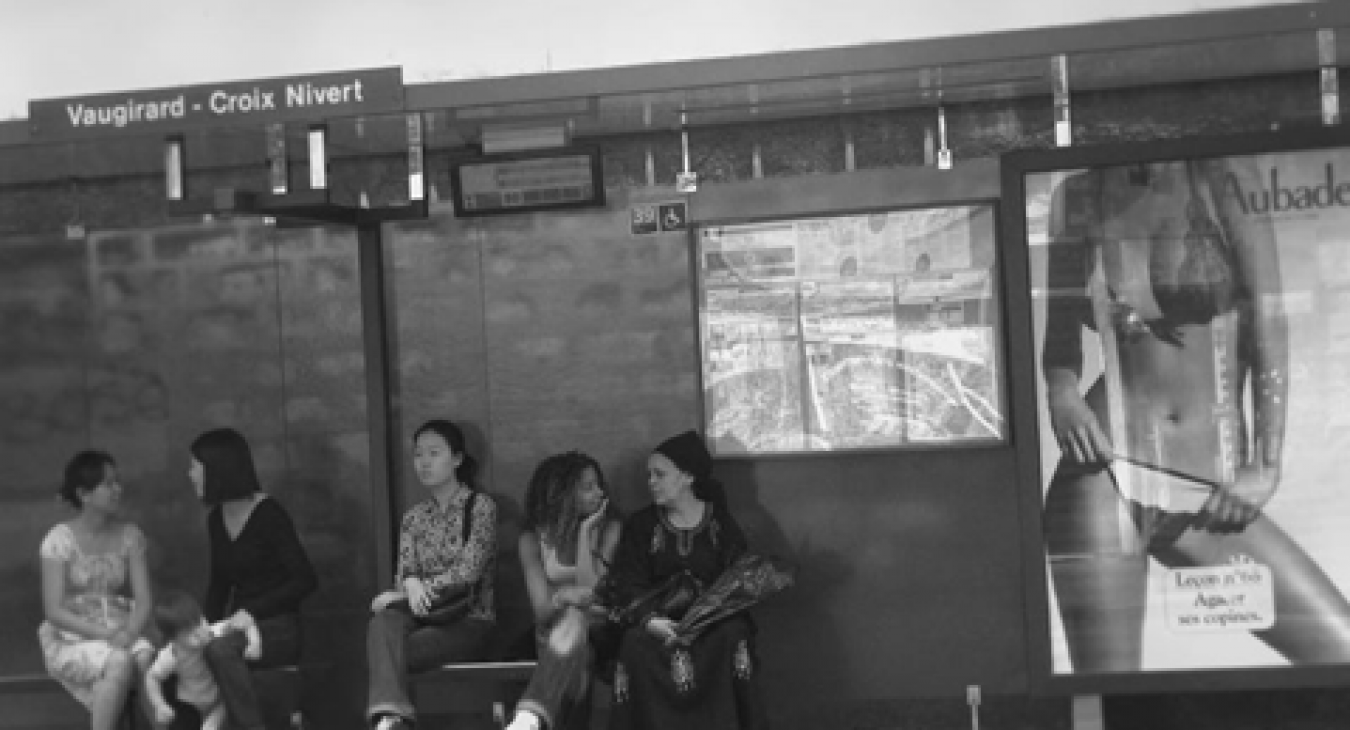 Photographie par Arslan (2016) provenant de Flickr, représentant des femmes attendant à un arrêt de bus où est affiché le corps fractionné d’une femme à but publicitaire.